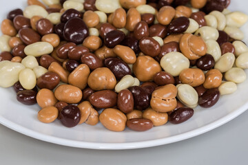 Raisins covered with dark, white and milk chocolate on dish