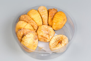 Dried figs in round plastic packaging on a gray background
