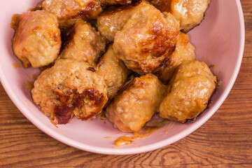 Prepared meat patties in bowl on rustic table close-up
