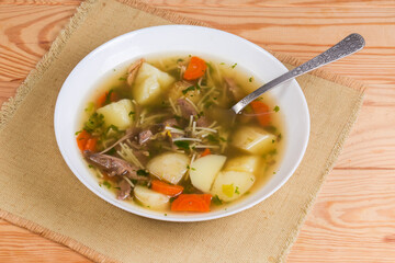 Chicken vermicelli soup in bowl with spoon on rustic table