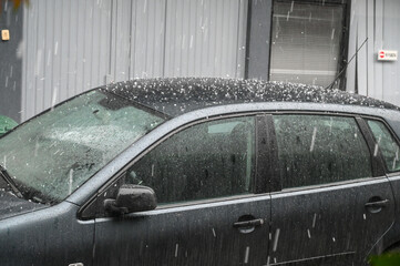 A lot of ice hitting a car. Hail storm in the city. Huge hailstone with heavy rainfall on the...