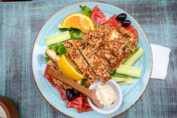 Fried meat with sesame and vegetables in a restaurant. Lunch served on a plate.