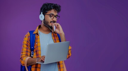 a dynamic Indian professional speaking on his Bluetooth headset, holding a laptop and wearing a backpack, displaying a concentrated pose on a purple background, providing room for text or graphic 