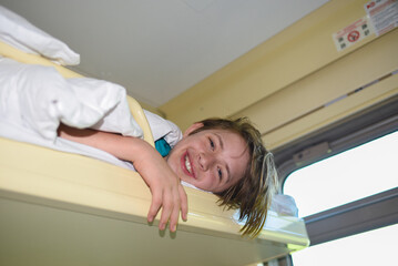 smiling happy boy lying on a long-distance train.