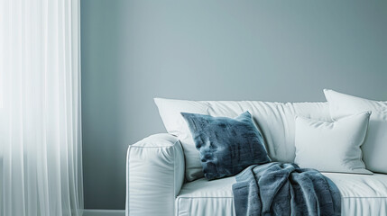 White sofa with blue throw pillow against grey wall, closeup view. Minimalist home interior design of modern living room in soft light
