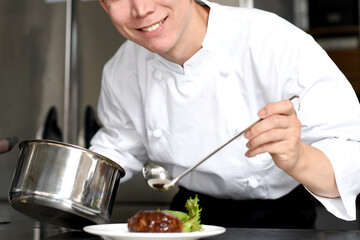 料理を皿に盛る若いアジア人の男性調理師