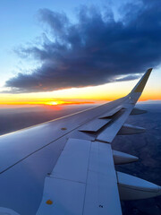 Fototapeta premium Orange Sunset View from an Airplane Window. A stunning view of the sunset from an airplane window, capturing the wing and the vibrant colors of the sky. 