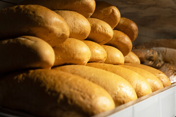 Freshly baked oval yeast bread on the shelf of a home bakery. Appetizing loaves of bread with golden brown crust on the grocery shelf. Close-up.