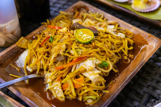 a plate of mouthwatering pancit canton with a slice of calamansi