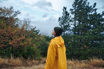 Alone traveler in a bright yellow raincoat admiring the sky on a remote dirt road