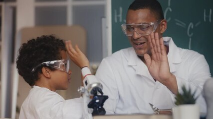 Boy and father playing scientists, doing lab research, giving high five, science