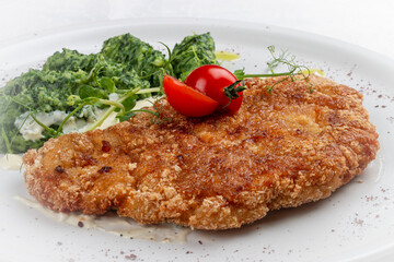 Chicken schnitzel served with sauce, accompanied by broccoli and cheese fritters.