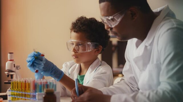 Boy observes reactions in test tubes, father documents results, playing science