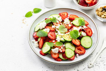 Refreshing cucumber strawberry  cheese salad  balsamic dressing on plate. Top view, flat lay, copy space.