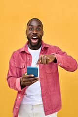Excited African American young man holding cellphone pointing at smartphone with wow face...