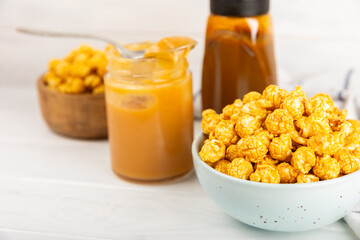 Sweet caramel popcorn in a bowl on a wooden background. Salted caramel popcorn. Caramel sauce. Close up. Topping. Place for text. Copy space