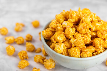 Sweet caramel popcorn in a bowl on a wooden background. Salted caramel popcorn. Caramel sauce. Close up. Topping. Place for text. Copy space