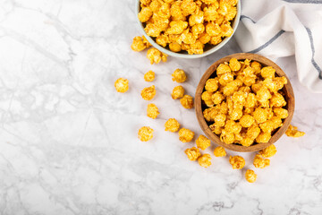 Sweet caramel popcorn in a bowl on a wooden background. Salted caramel popcorn. Caramel sauce. Close up. Topping. Place for text. Copy space