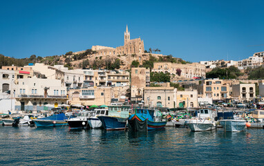 Scenic view of a coastal town with colorful boats, historical buildings, and a church on a hill...