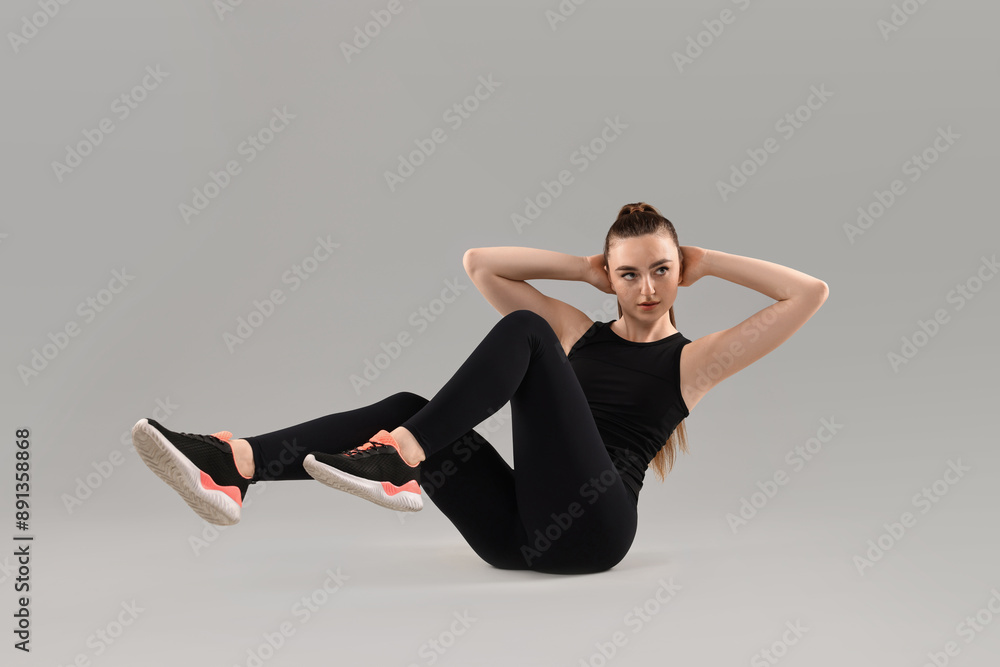 Wall mural Young woman doing aerobic exercise on light background