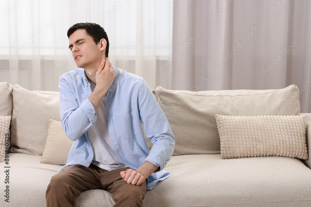 Canvas Prints Man suffering from pain in his neck on sofa indoors