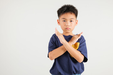 Portrait Asian young kid boy unhappy or confident standing holding two cross arms say no X sign,...