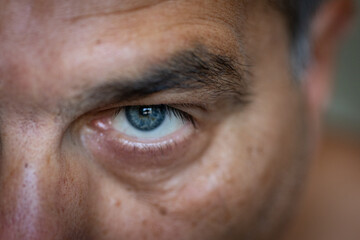 Close-up of an adult male's blue and grayish eye, with a focus on the eyelashes.