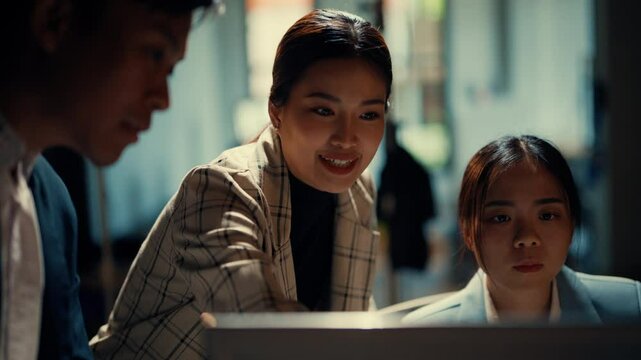 Three young professionals collaborate on a project in a modern office, discussing ideas and analyzing information on a computer screen, focused and engaged in teamwork