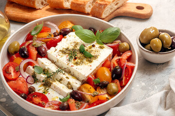 Healthy lunch or dinner with fresh feta cheese salad with organic tomatoes with olives and basil, olive oil and aromatic herbs