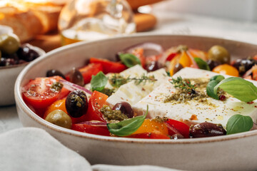 Healthy lunch or dinner with fresh feta cheese salad with organic tomatoes with olives and basil, olive oil and aromatic herbs