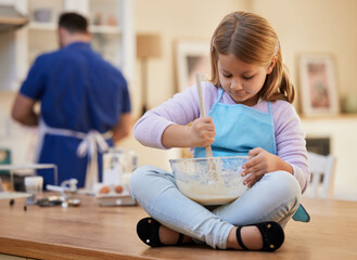 Girl, child and bowl for baking in kitchen on table with mixing batter for cookies, dessert or cake recipe. Cooking, kid or prepare ingredients for learning, development or culinary education in home