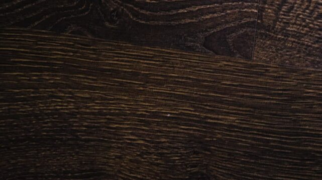Laminate flooring in slow motion camera slide. The flooring is walnut texture, parquet on the floor.