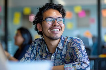 Hispanic male designer smiling looking up while working in busy open plan office