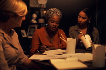 Business team, planning and fast food at night in office for company project, diversity or deadline. Digital agency, strategy and eating takeaway in workplace as women with burnout for collaboration