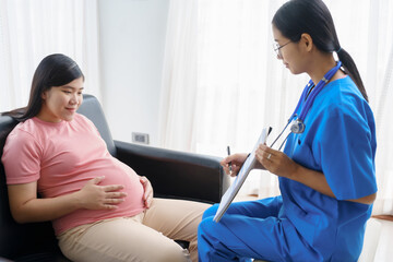 Obraz premium Pregnant mothers meet the nurse at the clinic as scheduled, reviewing their medical history and discussing symptoms. Sitting on the sofa, they report headaches, nausea, and back pain to the nurse.