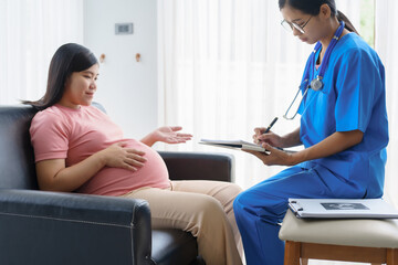 Obraz premium Pregnant mothers meet the nurse at the clinic as scheduled, reviewing their medical history and discussing symptoms. Sitting on the sofa, they report headaches, nausea, and back pain to the nurse.