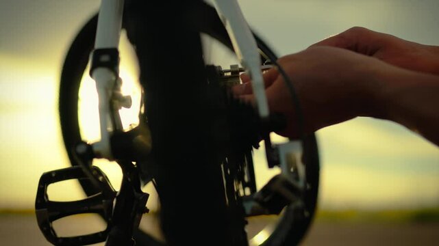 Long distance. A sporty man using a multitool repairs a bicycle on an asphalt road. General view of the camera, a white Caucasian man carries out repairs while traveling, a tourist