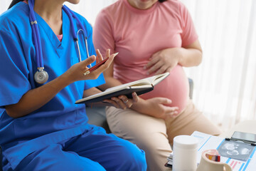 Pregnant mothers meet the nurse at the clinic as scheduled, reviewing their medical history and discussing symptoms. Sitting on the sofa, they report headaches, nausea, and back pain to the nurse.