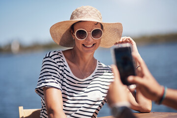 People, memory and happy picture of woman at harbor, vacation or adventure by waterfront in summer sunshine. Outdoor, mobile photography and smile with care, restaurant or bistro by sea for holiday