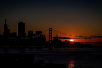 Fototapeta premium Sunrise over Bay Bridge silhouette against Frisco skyline