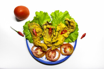 Photo of crispy fried mushroom food served on a plate and a bowl of sauce decorated with tomatoes and chilies on the side, on a white background. isolated