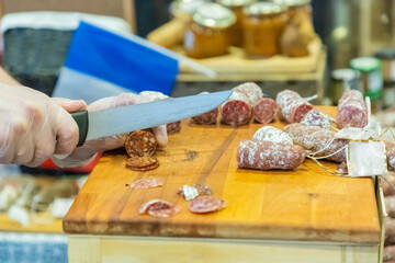 unrecognizable female hands cut a piece of salami