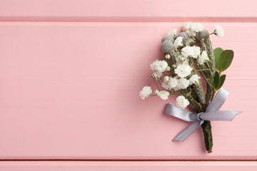 Small stylish boutonniere on pink wooden table, top view. Space for text © New Africa