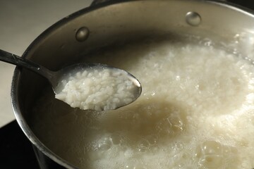Boiled rice in spoon over metal pot