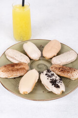 Assorted Eclairs with Various Toppings on Ceramic Plate and Fresh Juice - A Colorful and Delicious Breakfast or Dessert Option for Sweet Treat Lovers