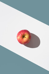 Una manzana roja sobre un soporte blanco y fondo verde. Vista superior	