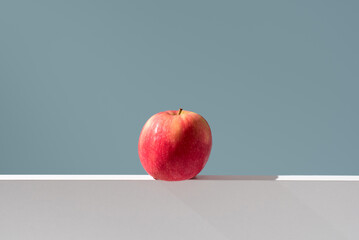 Una manzana roja sobre un soporte blanco y fondo verde	