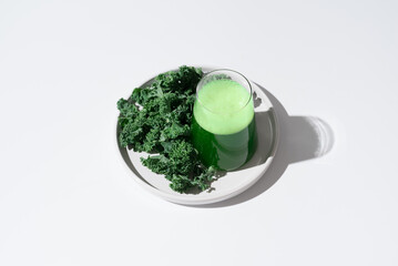 Batido de jugo de col rizada verde y hojas frescas de col rizada sobre fondo blanco