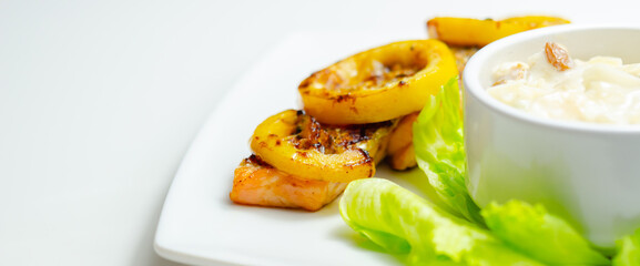 A plate of food with a piece of salmon and a couple of yellow slices of lemon