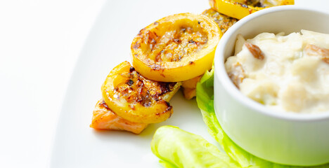 A plate of food with a piece of salmon and a couple of yellow slices of lemon